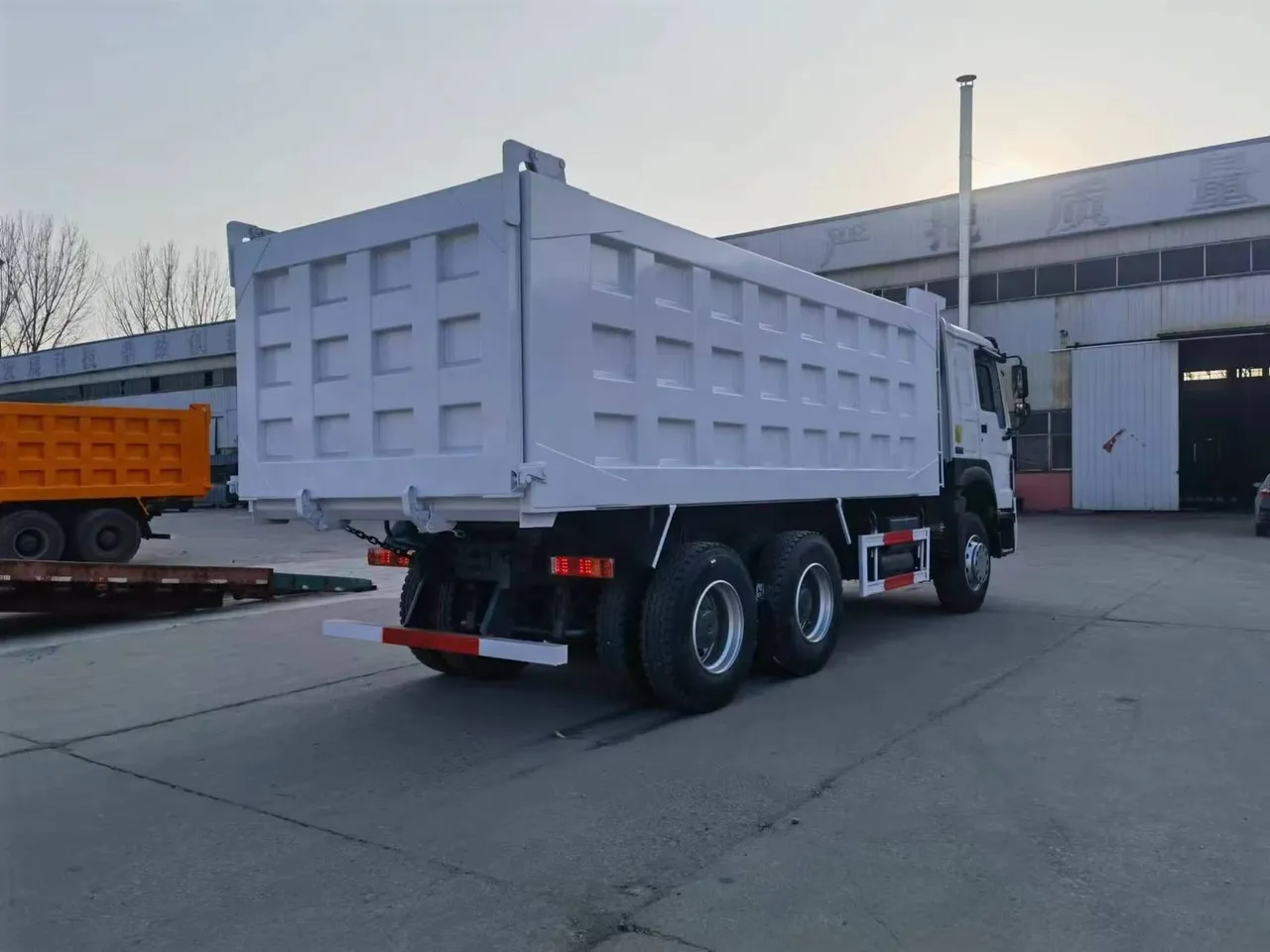 Row of 6x4 tipper trucks lined up at Chinese port ready for export